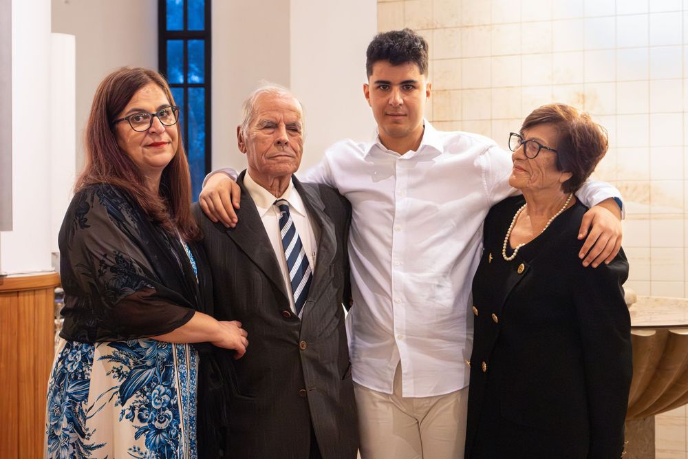 Four family members pose together smiling at a formal event, older couple flanking a young man and elderly woman.