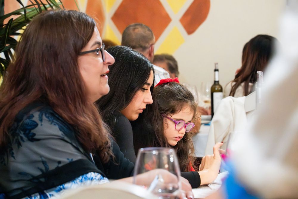 Three women dining together at a restaurant table, engaged with their phones during a social gathering.