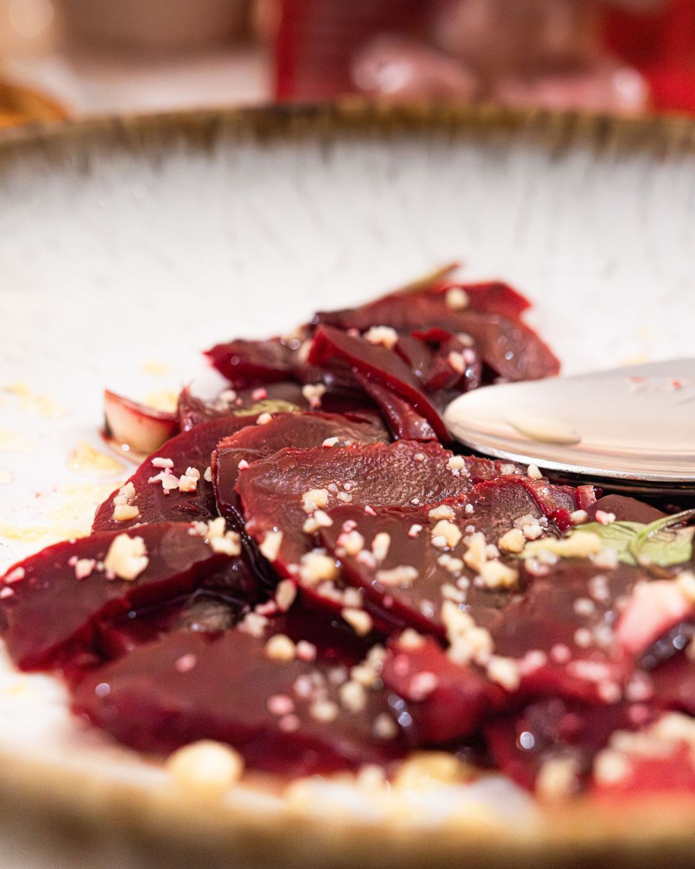 Sliced roasted beets with crumbled feta cheese and herbs served on a rustic ceramic plate.