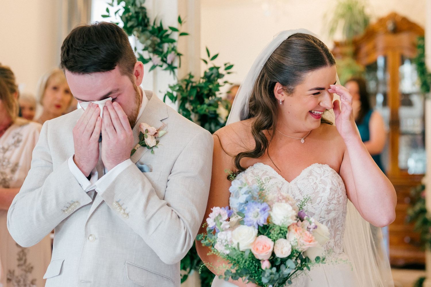 Emotional bride and groom crying tears of joy during their wedding ceremony, bride holding pastel bouquet.