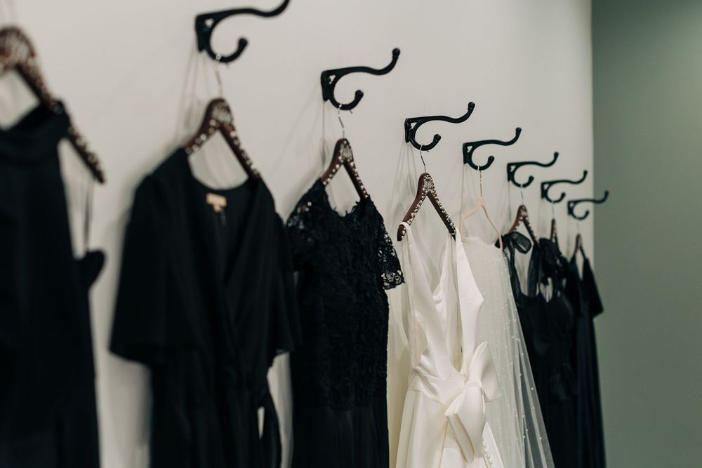 Black and white bridesmaid robes and dresses hanging on wall hooks in a bridal getting ready room.