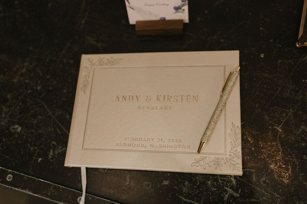 Custom wedding guest book for Andy and Kirsten with gold pen on a dark surface.