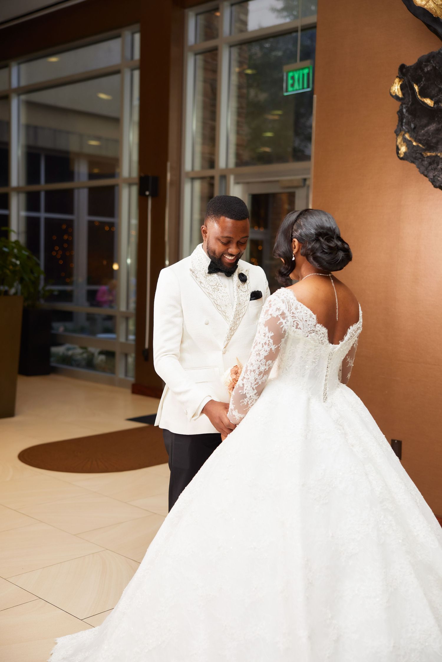 Bride and groom share a romantic first dance moment in elegant wedding attire inside a grand hotel ballroom.