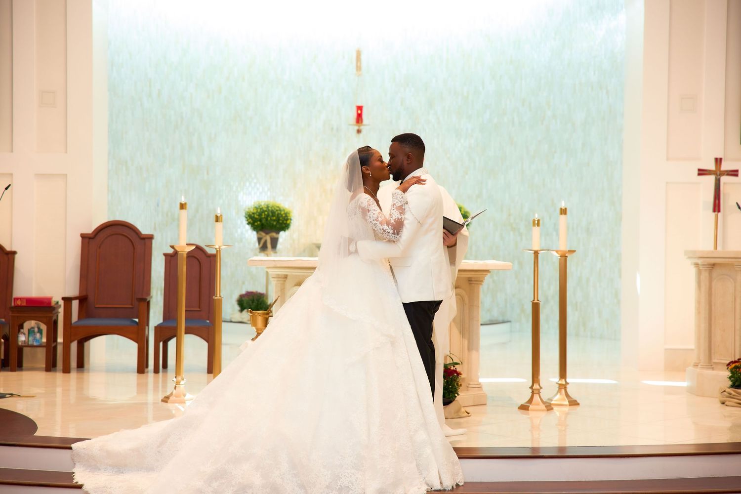 Bride and groom sharing a romantic kiss at the altar of a decorated church during their wedding ceremony.