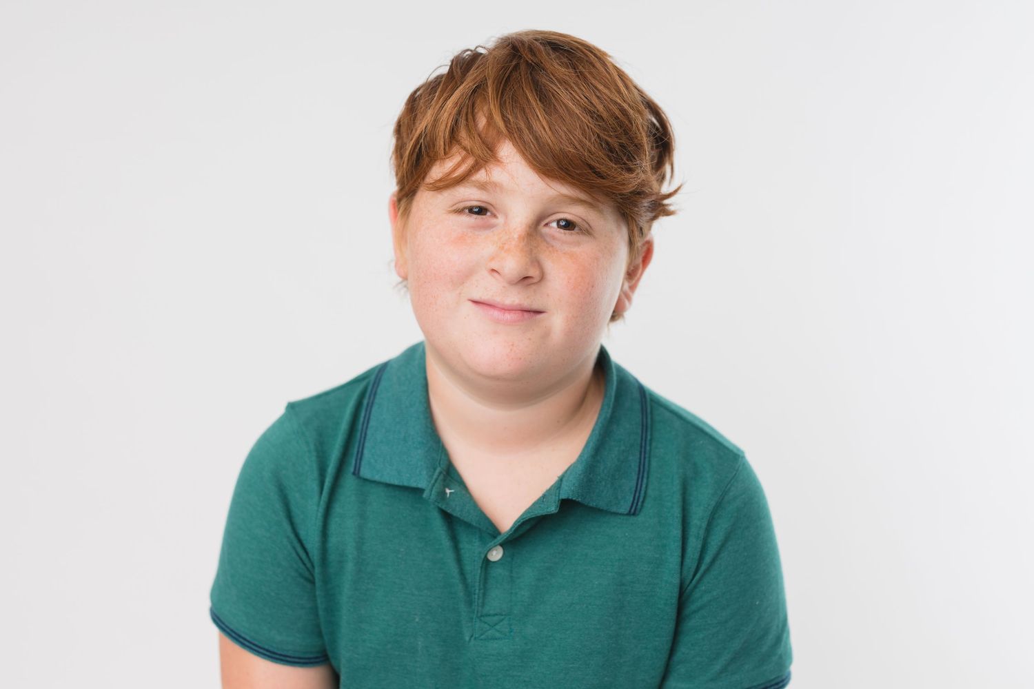 Studio portrait with pink shirt and baseball cap against white background.