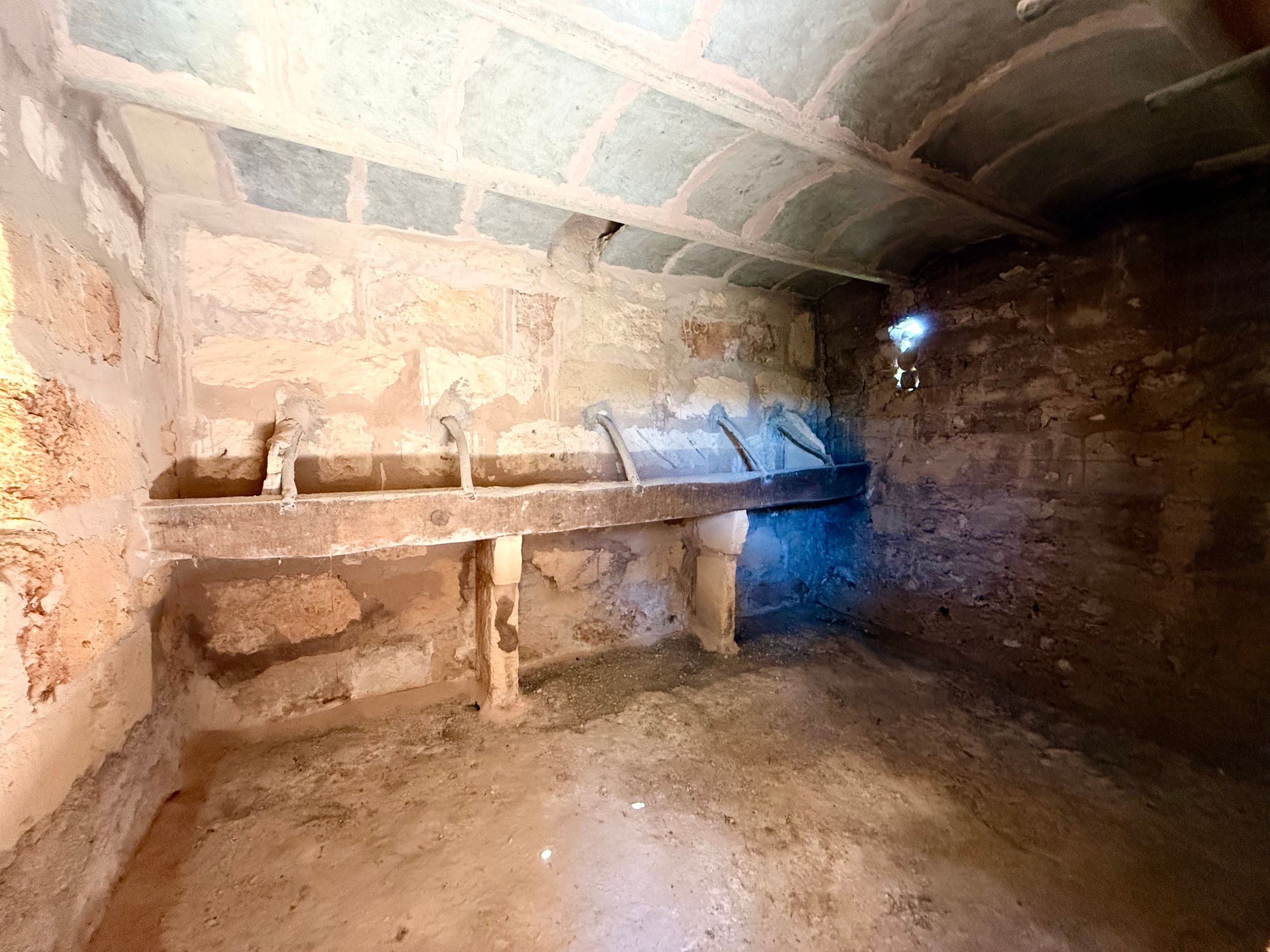 Ancient stone tomb interior with carved sarcophagus, illuminated by blue light, featuring weathered walls with faded frescoes.