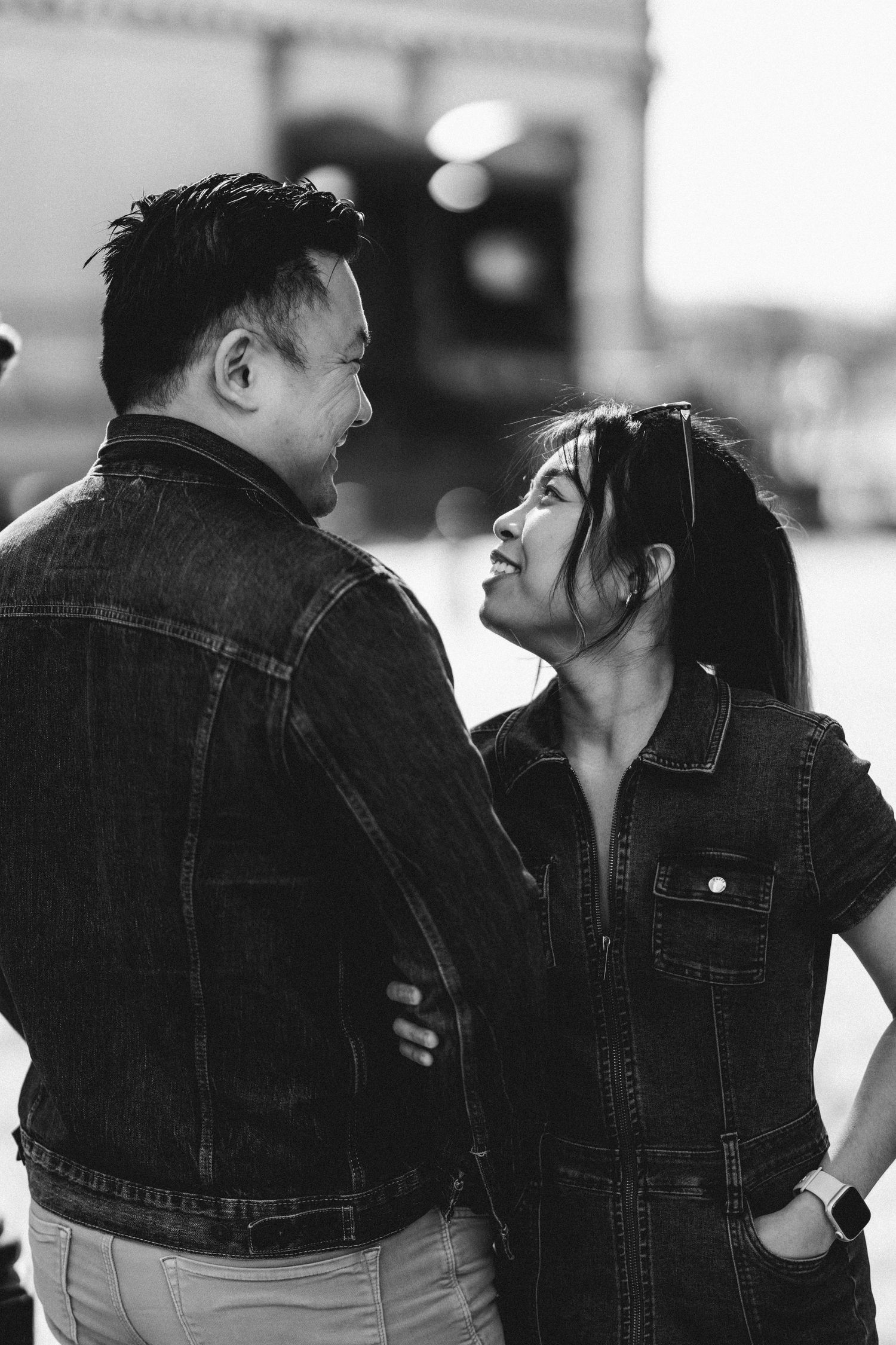 Black and white close-up of an Asian couple sharing a tender moment, woman smiling up at man.