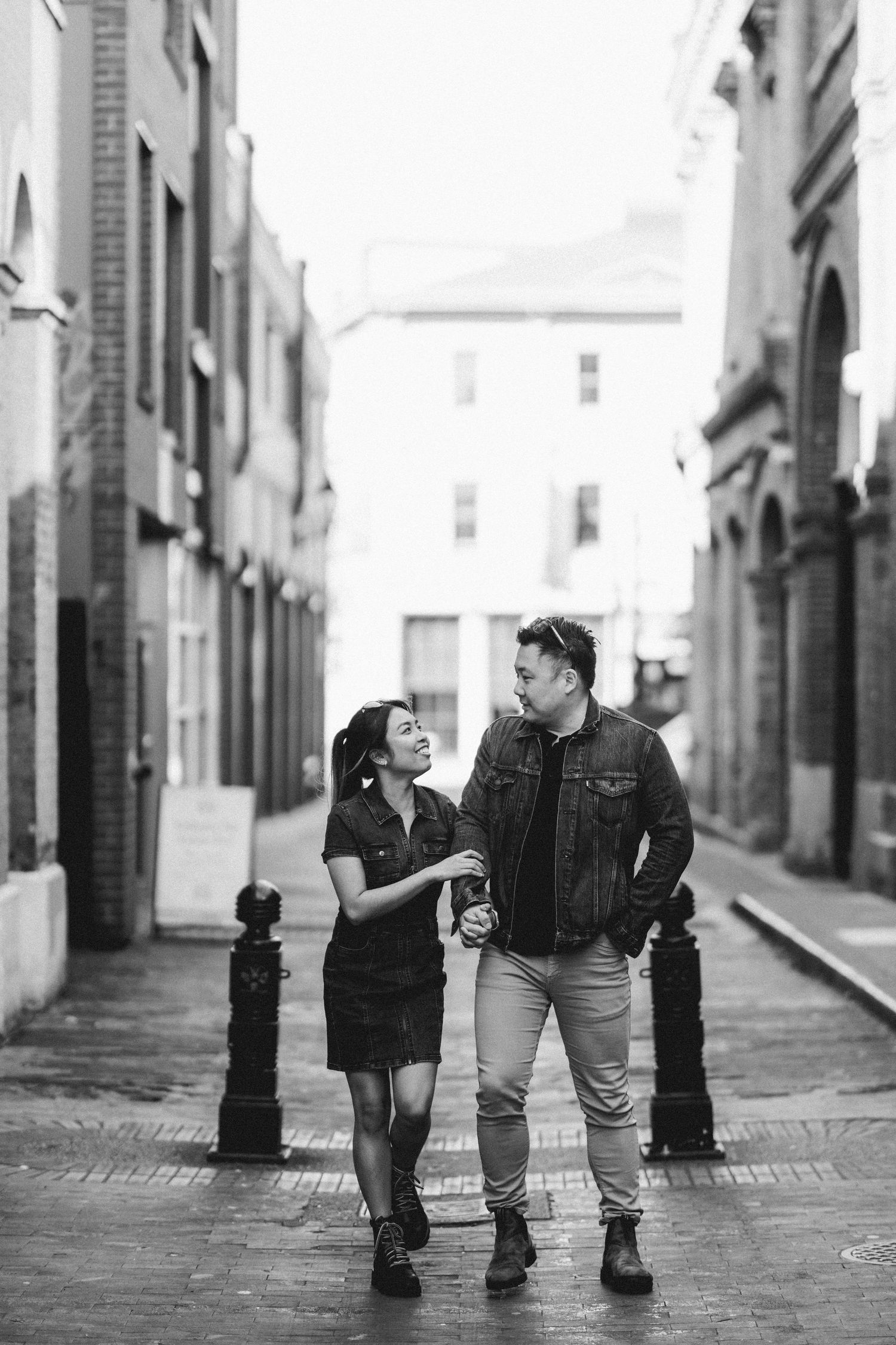 Black and white photo of a couple laughing together on a cobblestone city street.