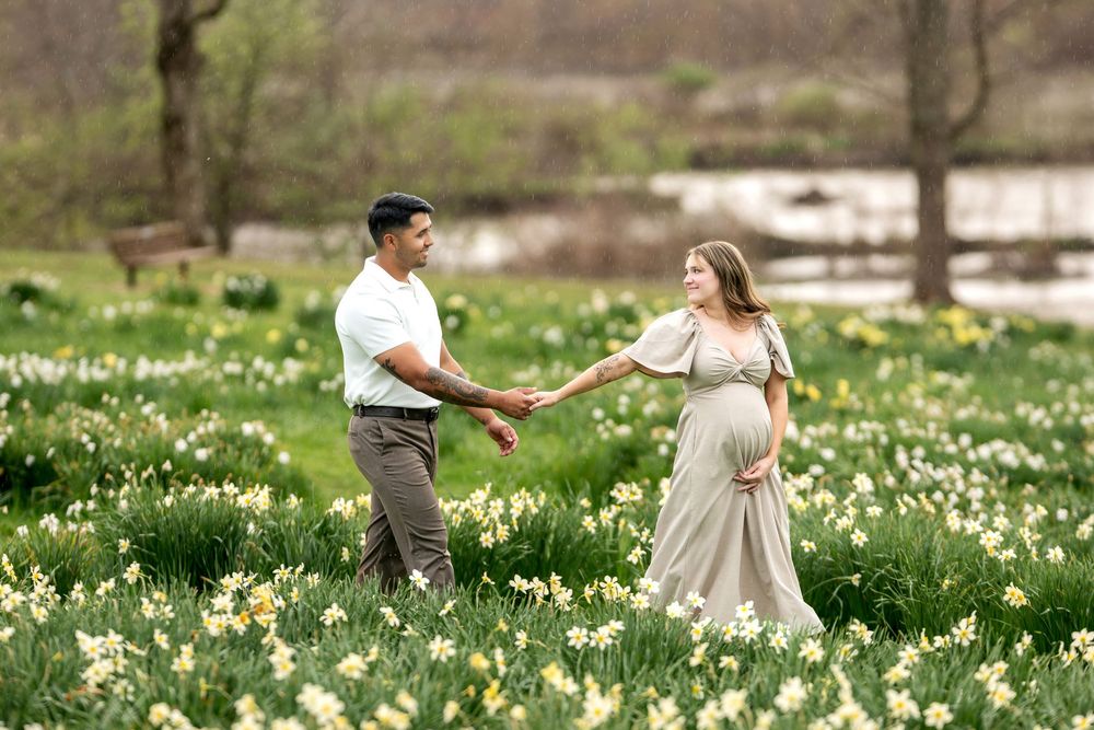 Couple holding hands and walking through a blooming daffodil field in spring.