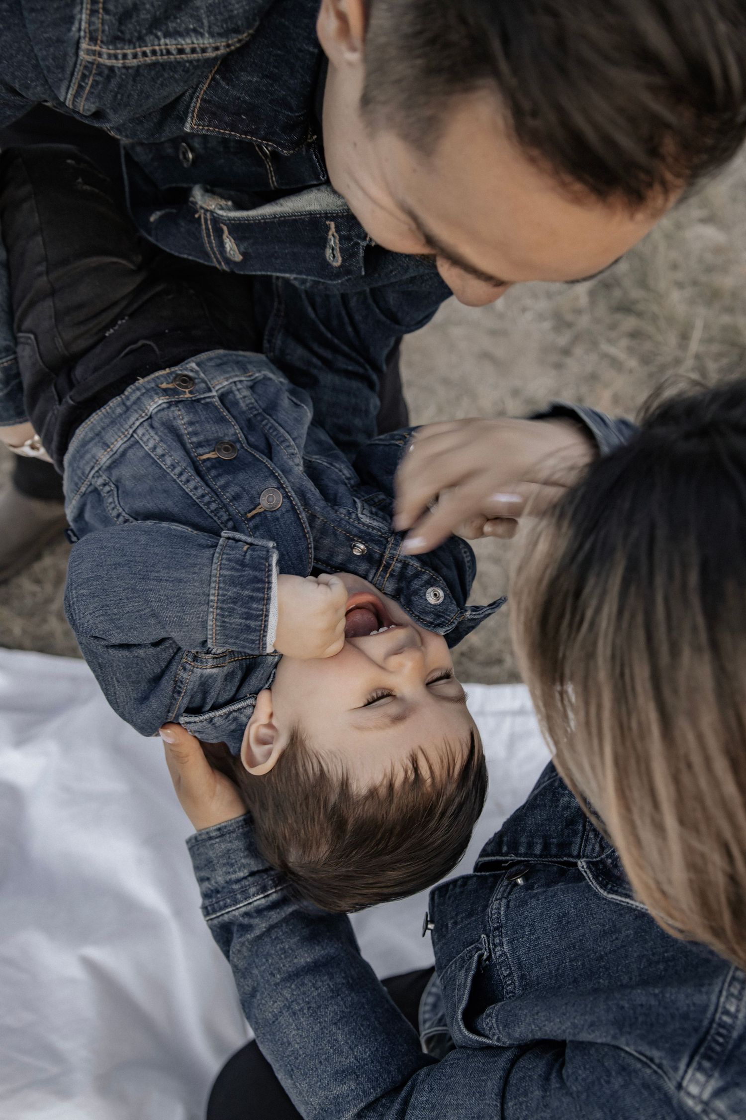 Family with young toddler all laughing together while dad hold toddler
