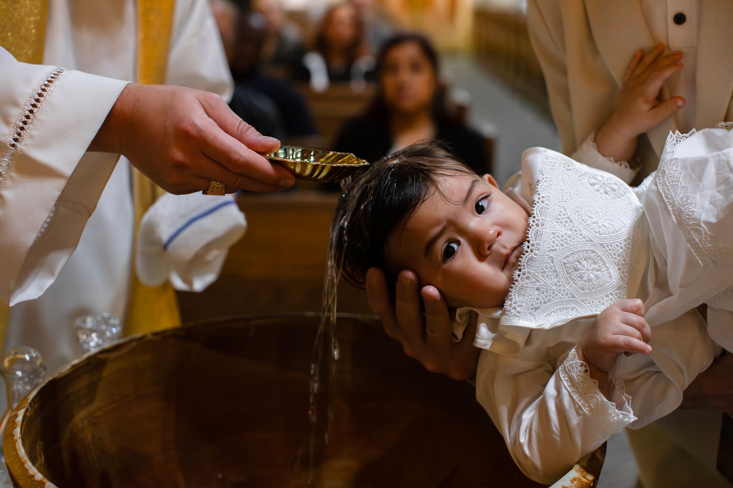 Water is poured over a child's head during a traditional baptism ceremony.
