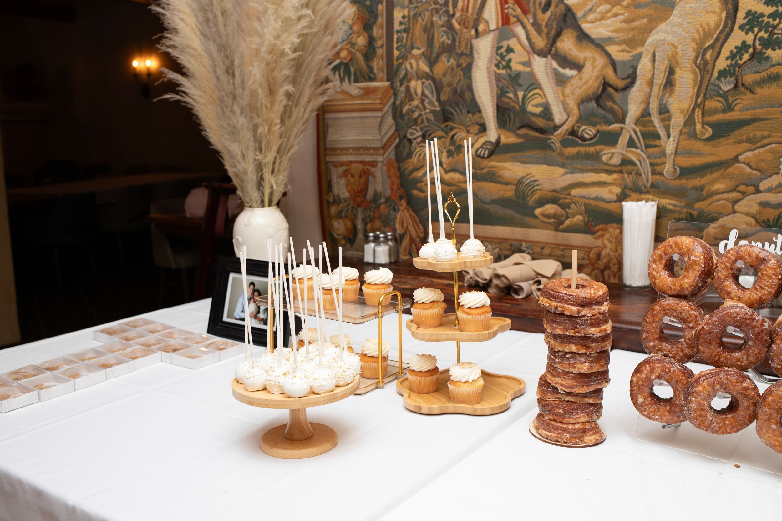 Elegant dessert table with cake pops, cupcakes and pretzels arranged on tiered stands.