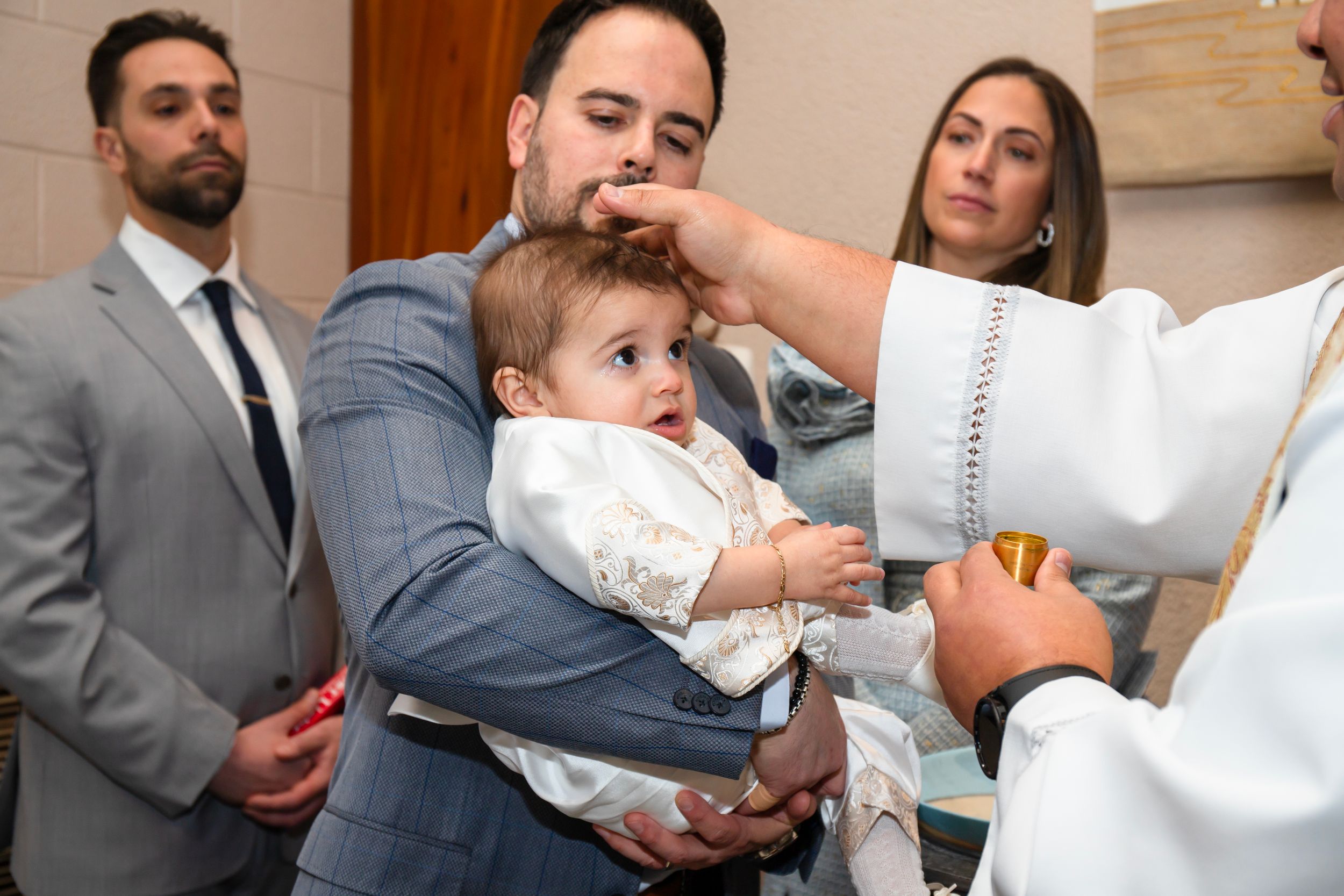 Close-up of baptism ceremony with priest performing blessing on infant.