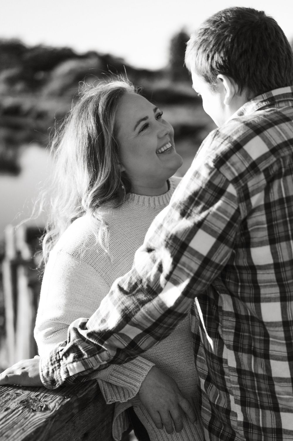 Black and white photo series showing a romantic couple embracing and laughing together outdoors.