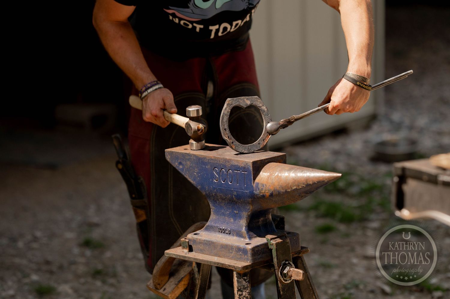 Farrier shaping a horseshoe on a Scout anvil with hand tools.