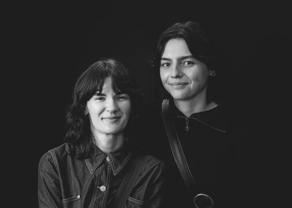 Black and white portrait of two people side by side, both with dark hair and warm expressions.