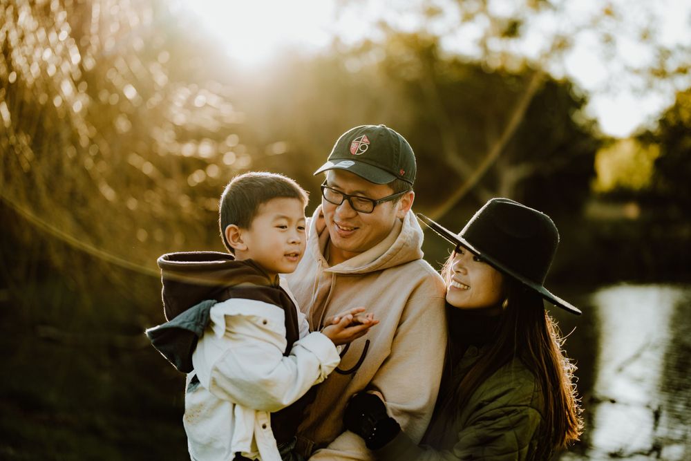 Family enjoying a tender moment together outdoors during golden hour by a lake.