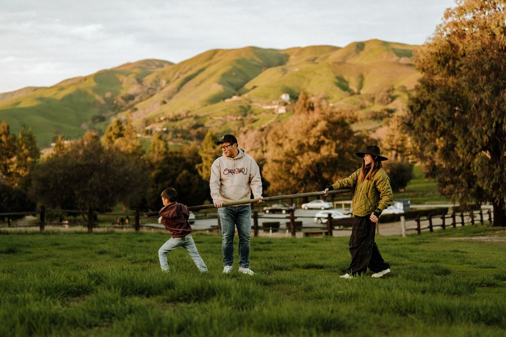 Small group playing together in a grassy field with golden hills in the background during sunset.