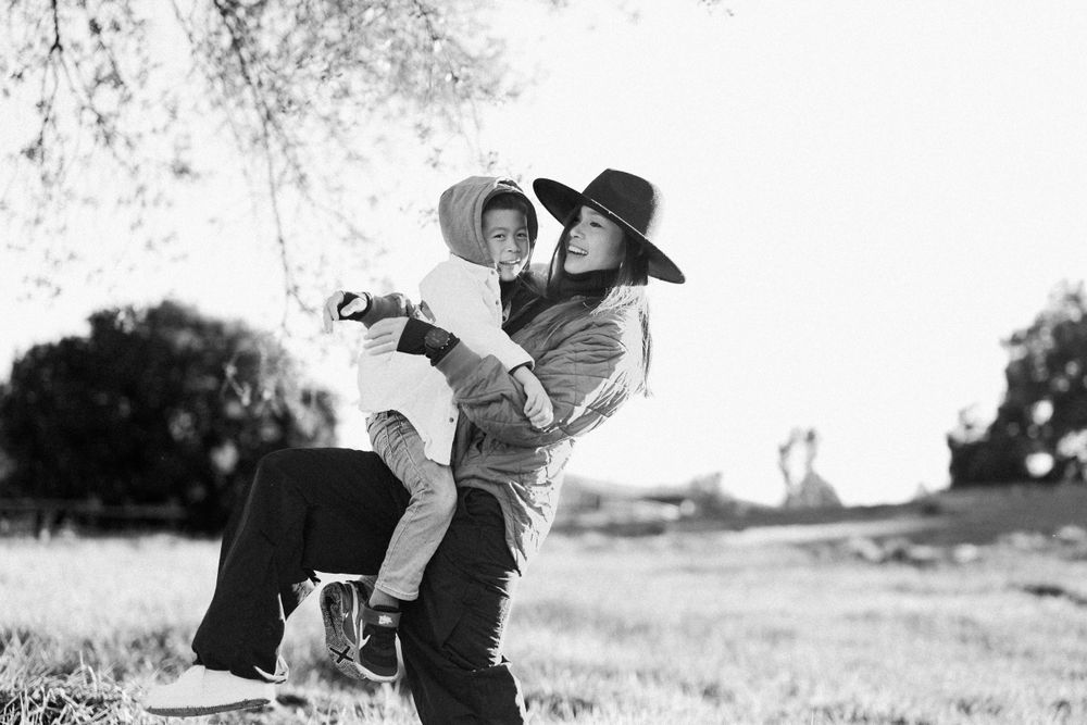 A joyful black and white candid moment of embracing figures outdoors in a rural setting.