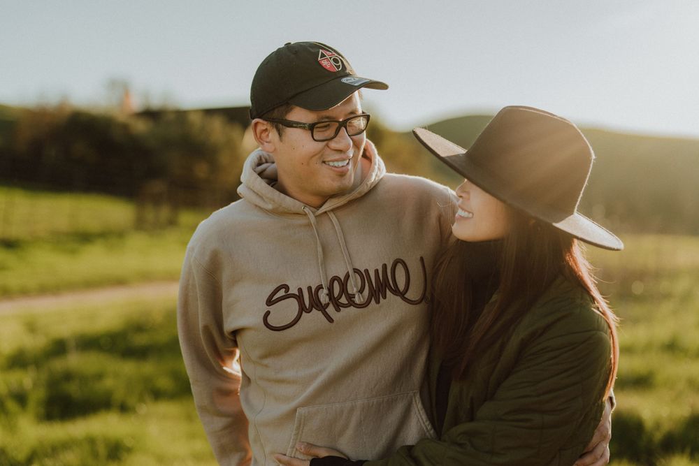 A couple sharing a tender moment outdoors at sunset in a grassy field on a warm evening.