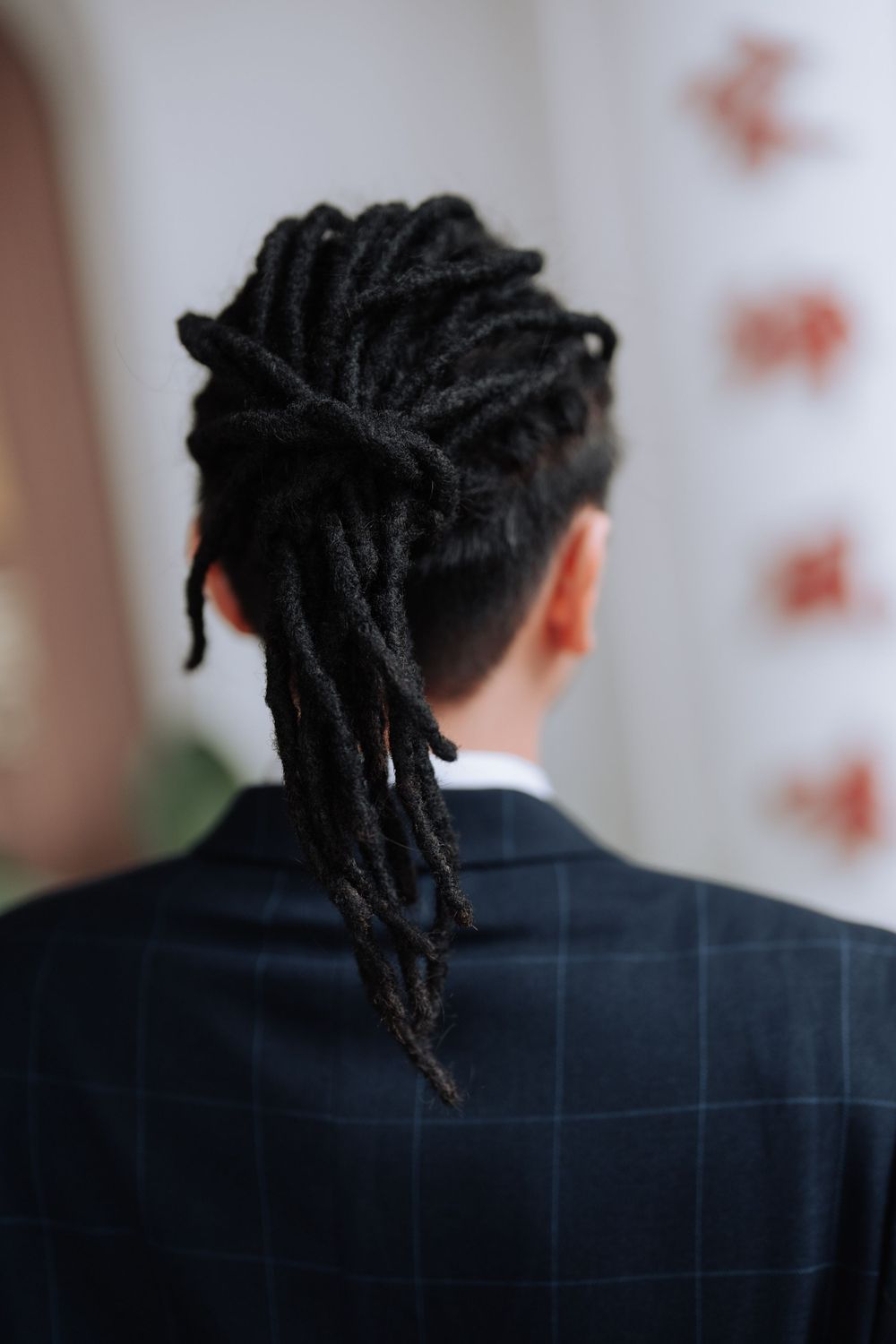 Back view of styled dreadlocks against a navy checked suit jacket.