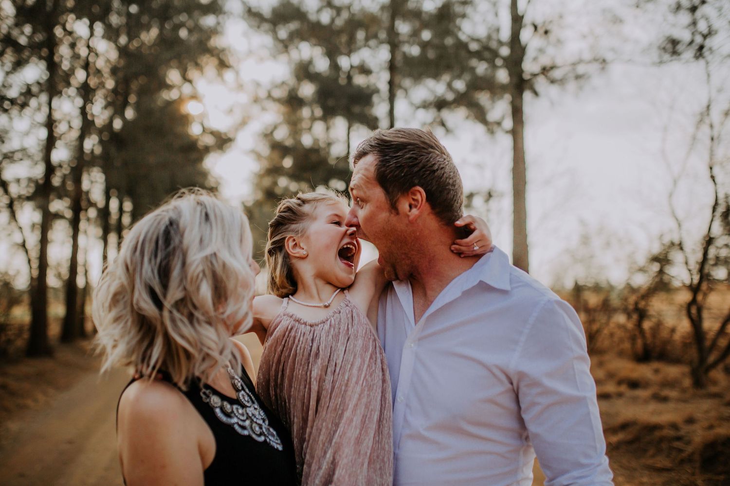 A joyful outdoor family moment captured in warm golden light with natural backdrop.