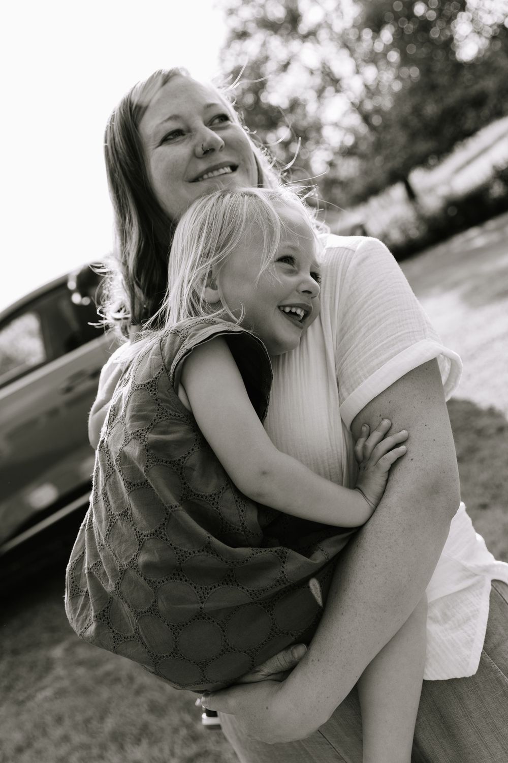 Black and white photo series showing playful embrace between two people outdoors in casual setting.