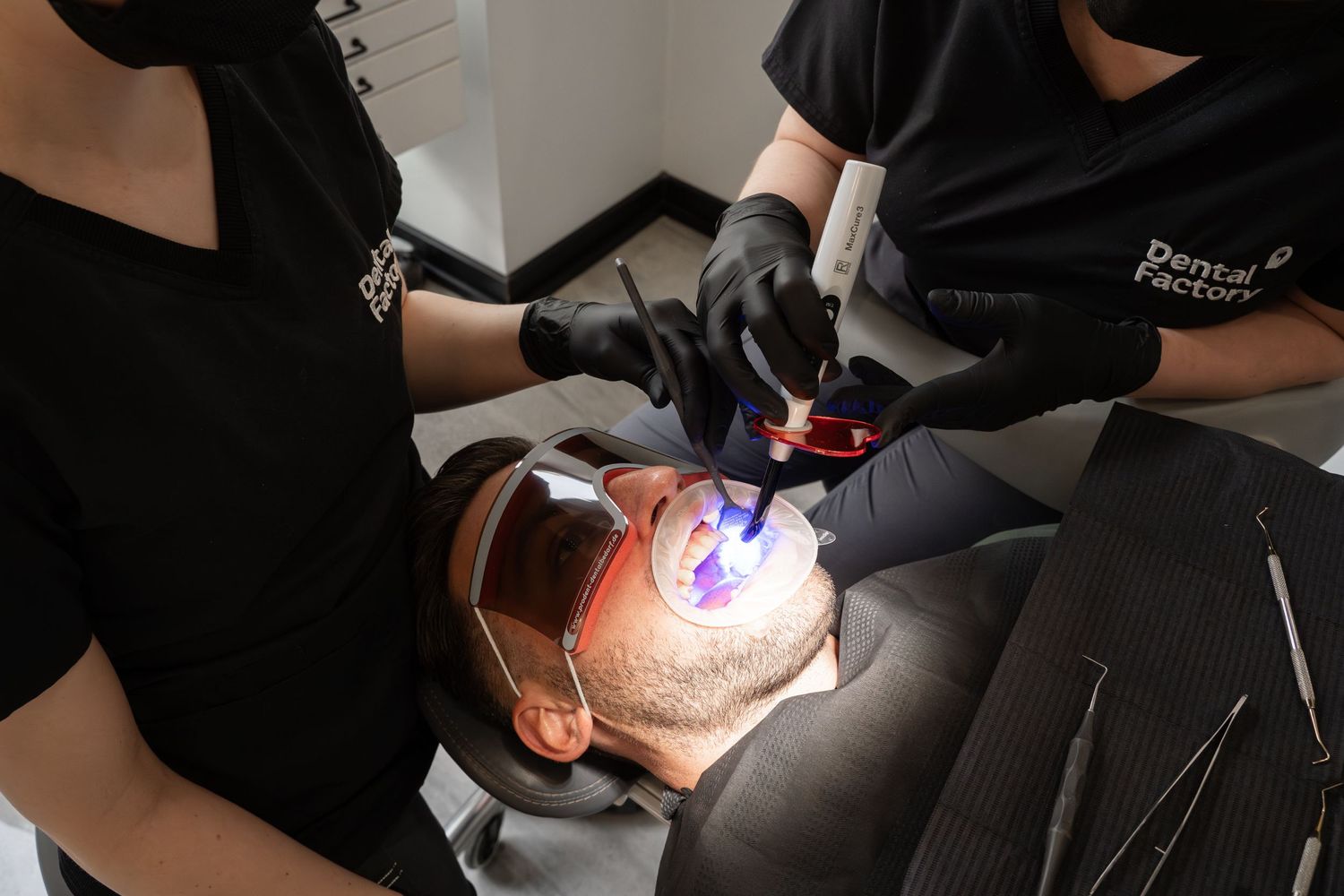 Close-up of cosmetologist performing facial treatment with UV light and protective equipment.