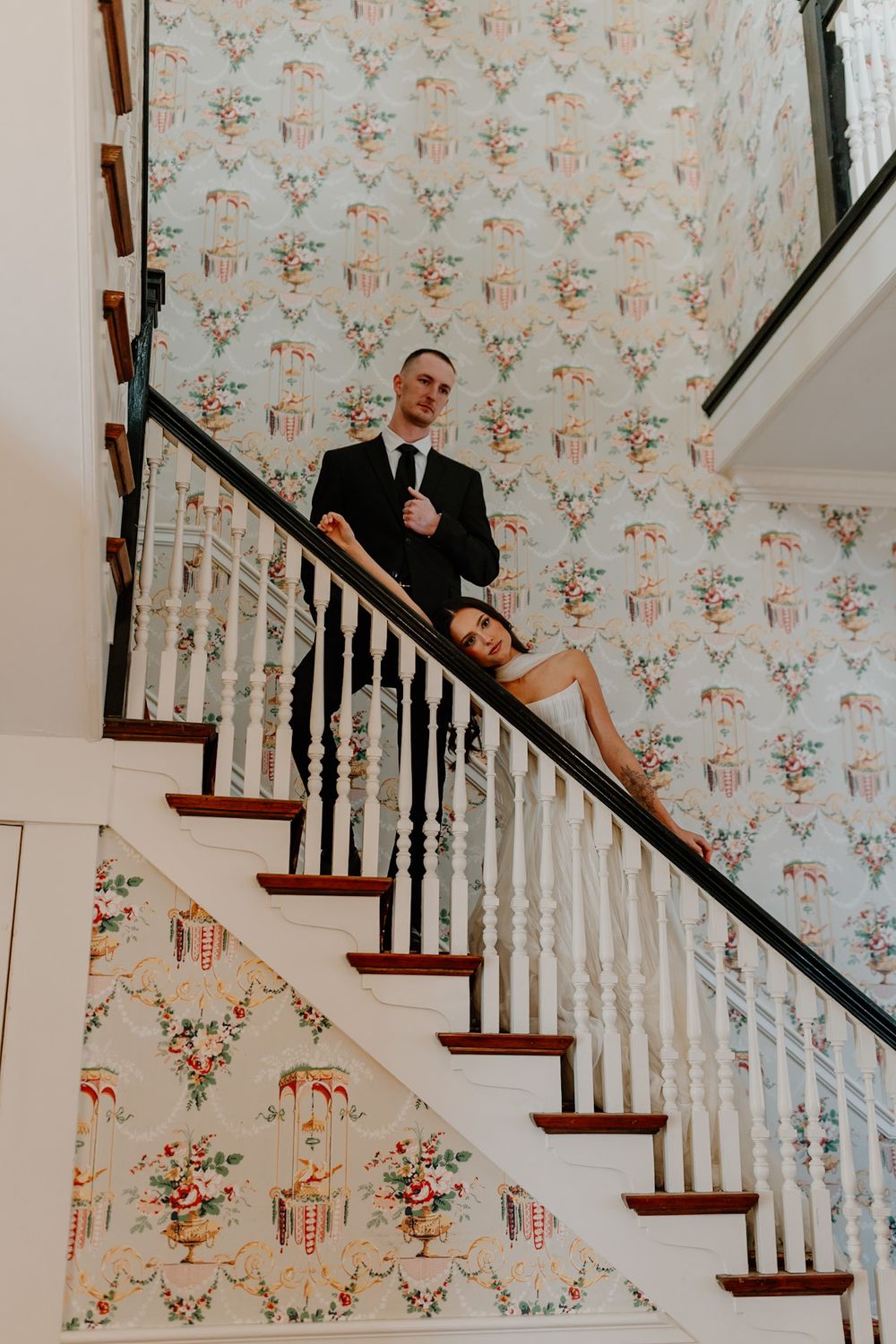 Creative staircase portrait with floral wallpaper backdrop.