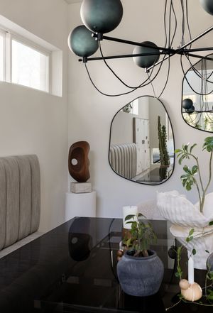 Modern dining room with globe chandelier, mirror, and sculptural decor.