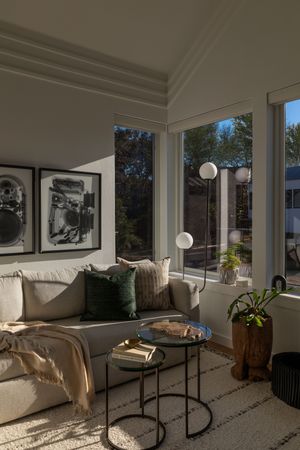 Cozy living room corner with beige sectional, black and white artwork, and large windows letting in natural light.