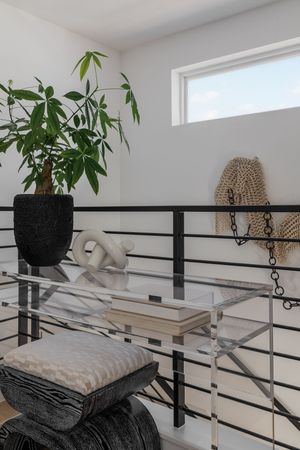 Modern stairway landing with black railings, potted plants and decorative cushions.