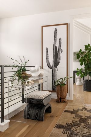 Minimalist hallway with black railings featuring large cactus artwork and southwestern decor elements.