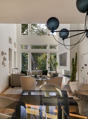 Bright living and dining space with high ceilings, large windows, and modern black pendant lighting.