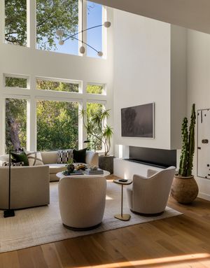 Contemporary living room with vaulted ceiling, floor-to-ceiling windows, and neutral curved seating.