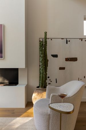 Cozy modern living room corner featuring a plush white chair and built-in fireplace with natural wood floors.