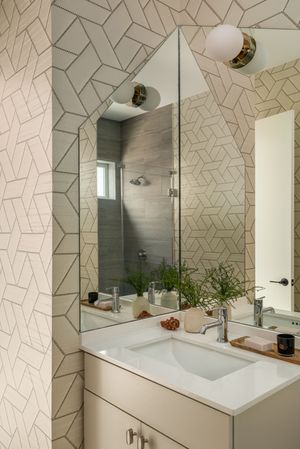 Modern bathroom featuring geometric wallpaper, floating vanity, and contemporary globe light fixtures.