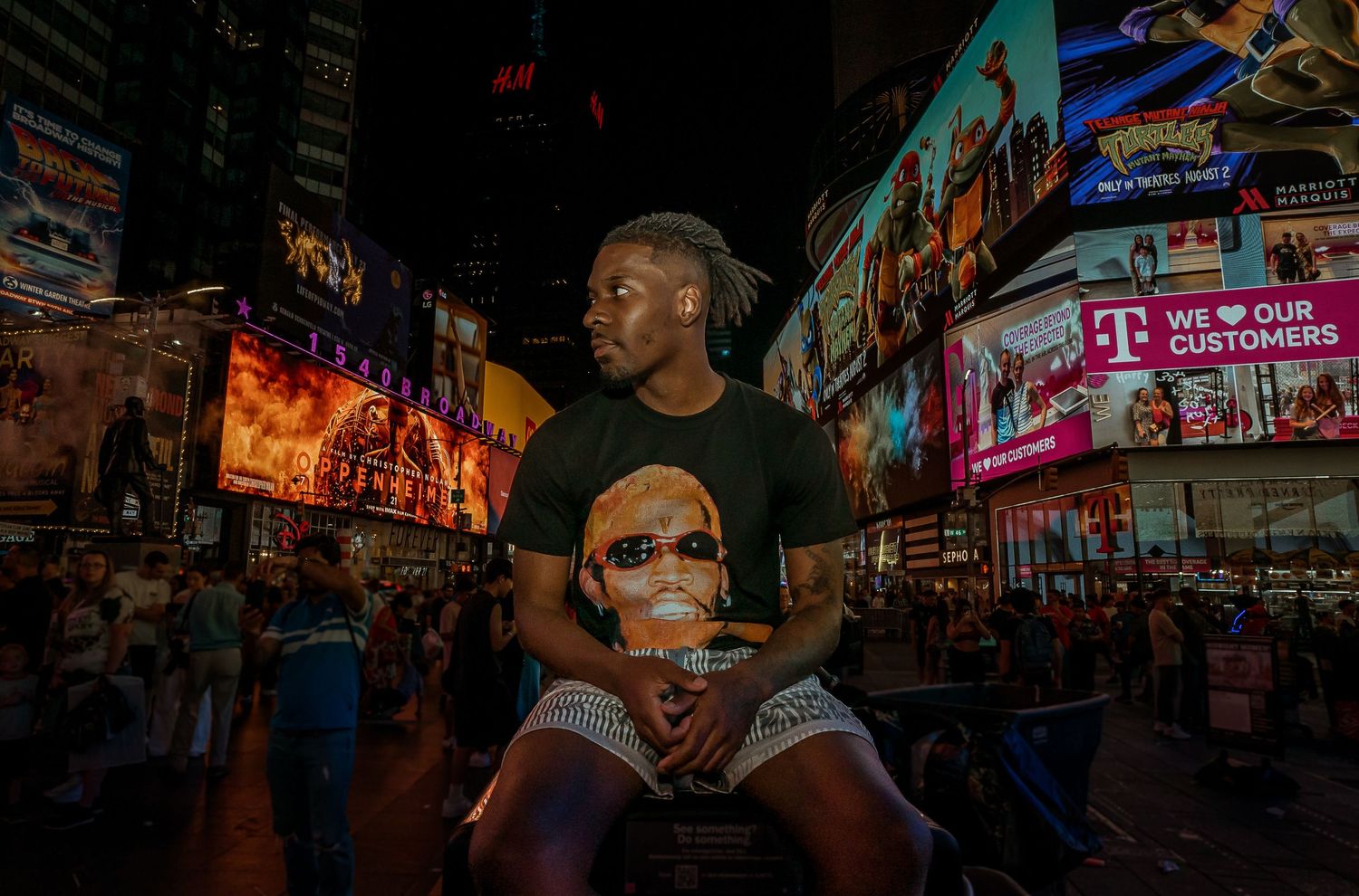 Vibrant nighttime scene in Times Square with bright neon billboards and someone seated on another's shoulders amidst city lights.