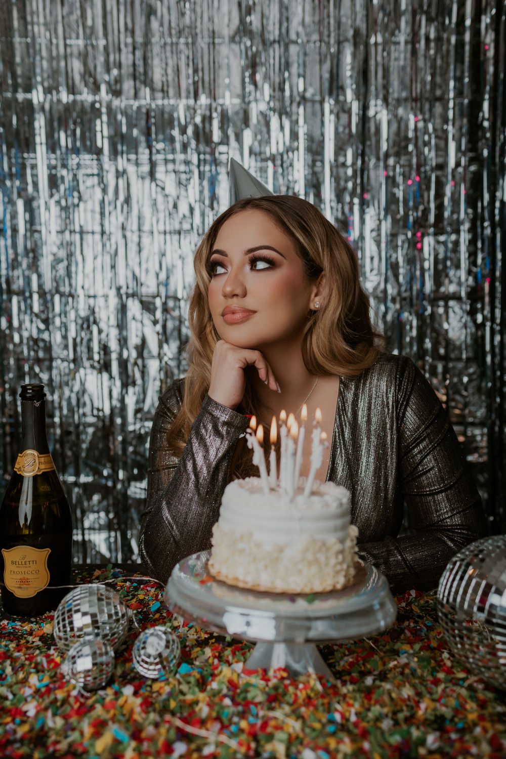 Birthday celebration scene with silver tinsel backdrop and white cake with candles.