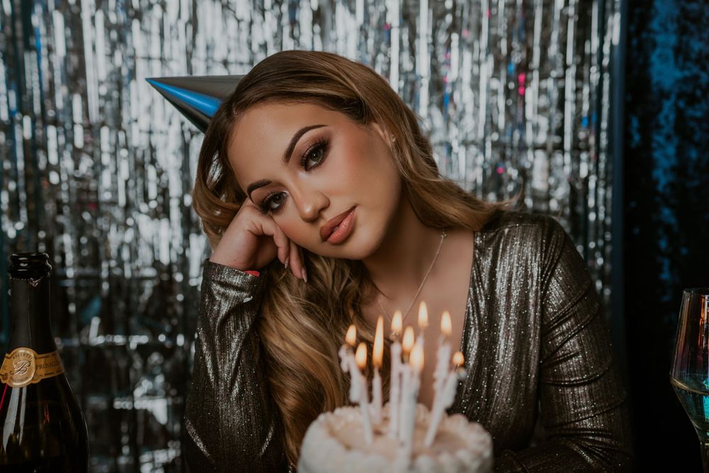 Elegant birthday portrait with sparkly backdrop and candlelit cake.