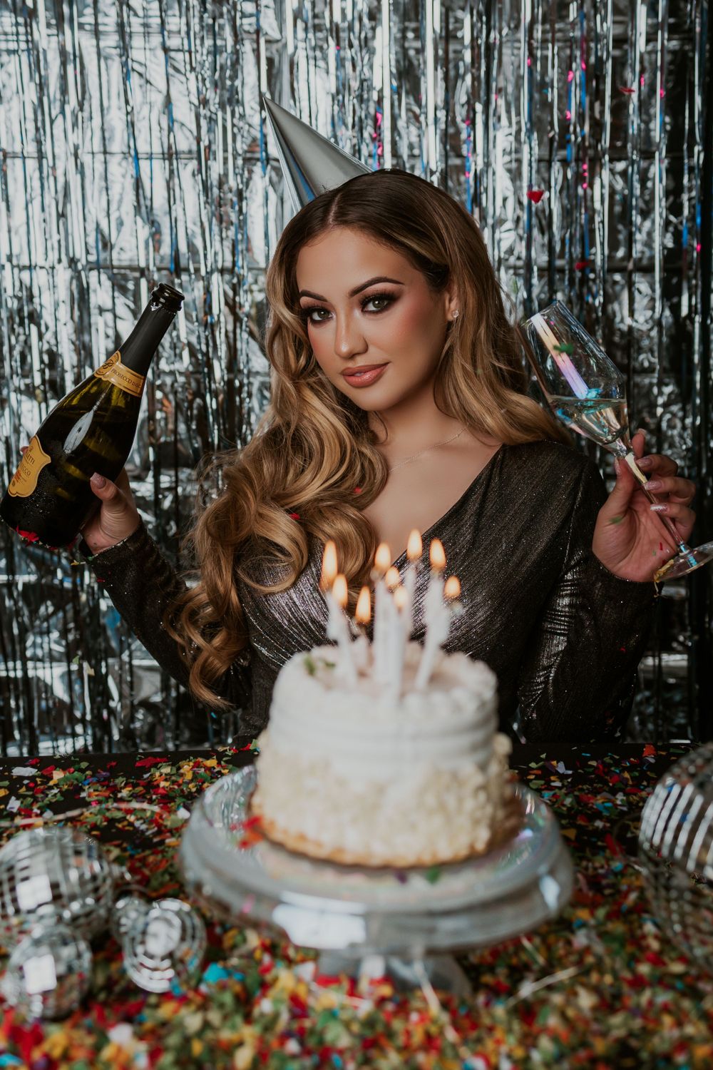 Celebratory scene with champagne bottles, birthday cake and silver tinsel background.
