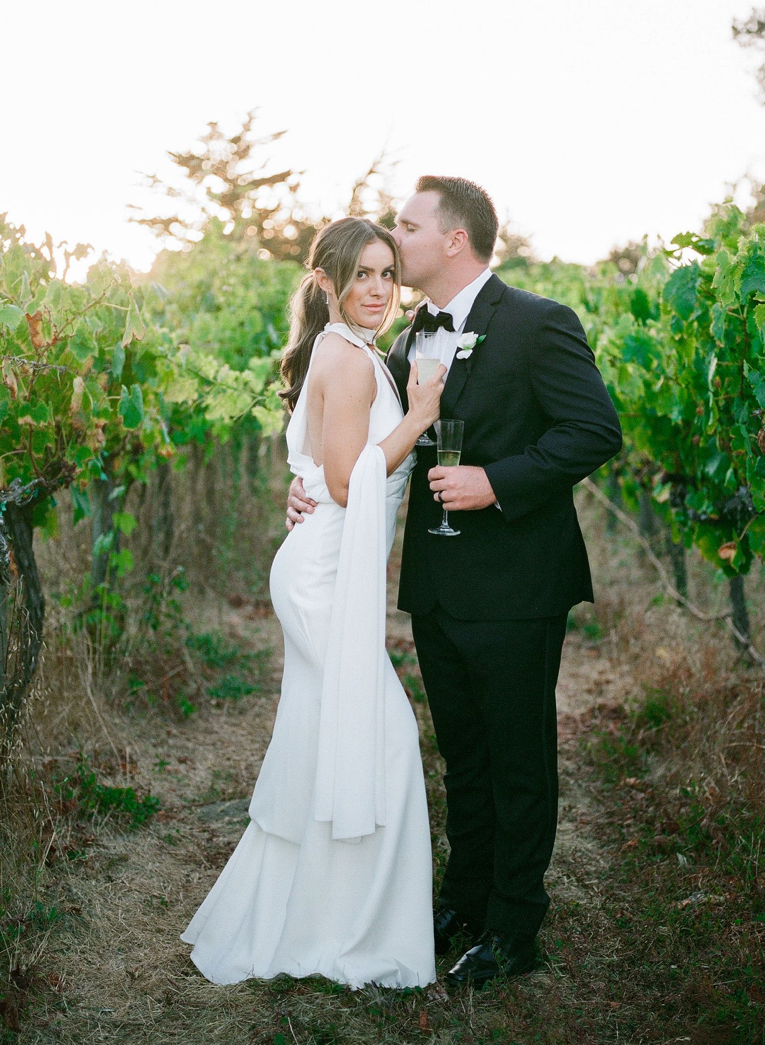 Black and white romantic wedding photo showing close embrace between couple in white formal attire.