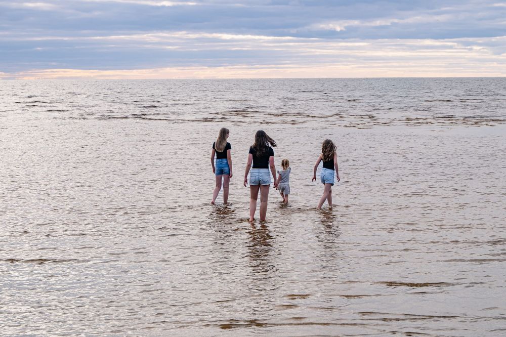 Quatre enfants de dos jouant dans l’eau à la plage de Saint-Gédéon.