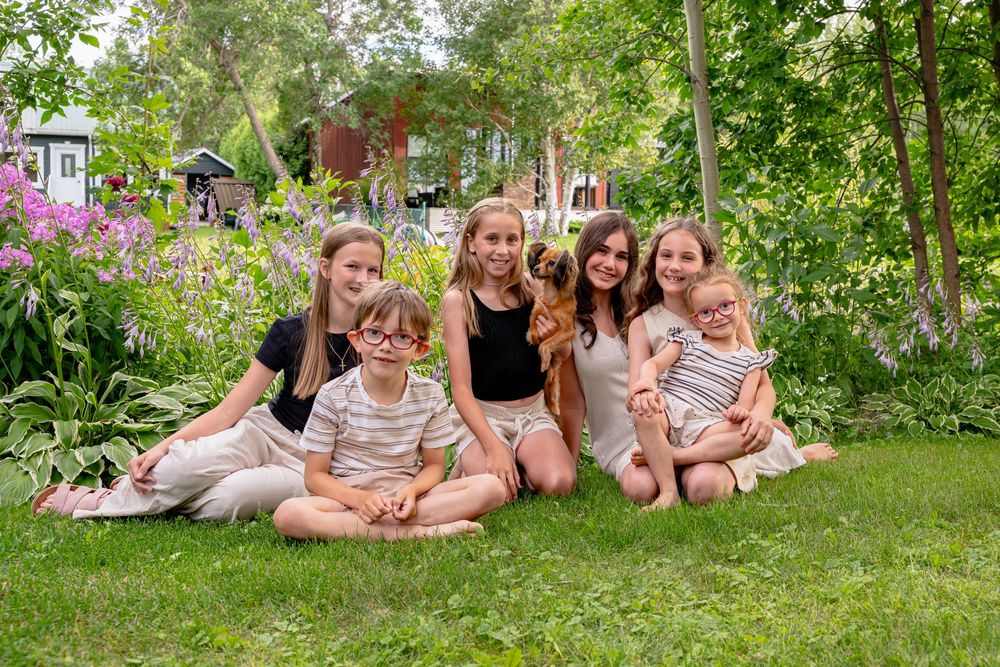 Cinq jeunes enfants assis par terre avec un chien souriant à Saint-Gédéon.