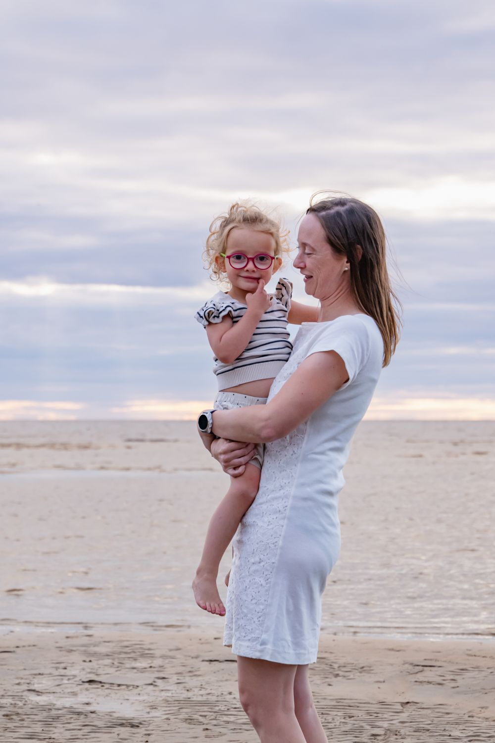 Maman tenant sa fille dans ses bras à la plage de Saint-Gédéon, la regardant avec un sourire