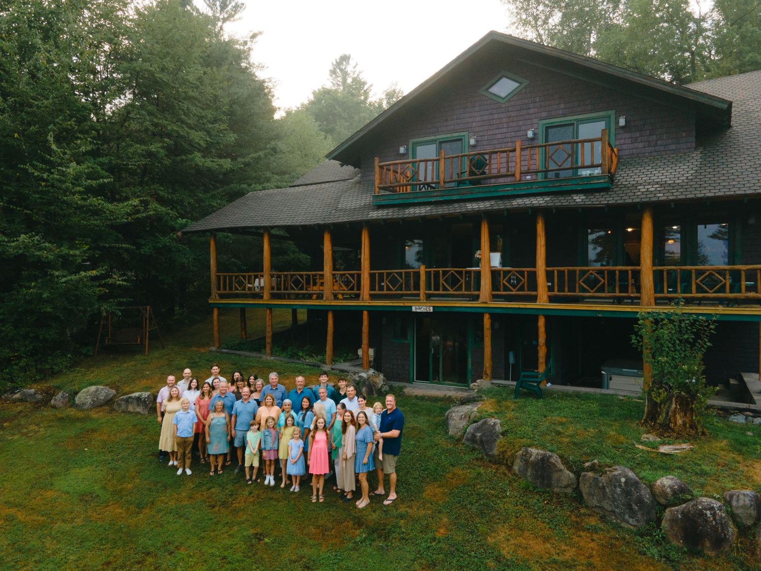 A series of photos showing a rustic wooden lodge and groups of people gathered on its lawn during a summer gathering.