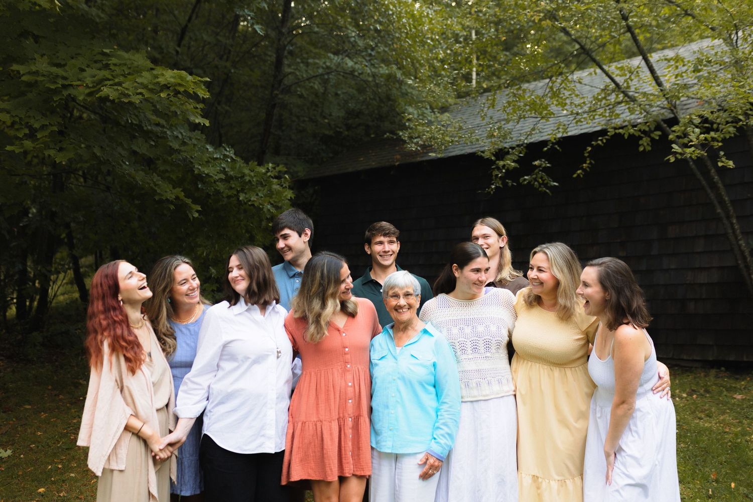 Group of people gather together in a natural outdoor setting wearing light colored clothing.