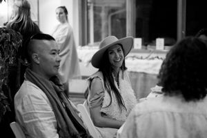 Black and white photo of people engaged in conversation at an indoor social gathering.