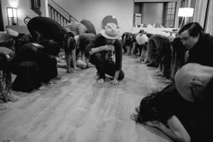 Black and white photo of people bowing down in rows during a spiritual gathering.