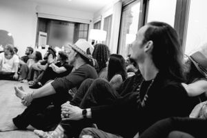 Black and white photo of audience members sitting casually during an indoor performance.